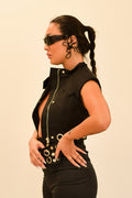 Woman wearing a black outfit with silver accents and olive green futuristic sunglasses on a beige background